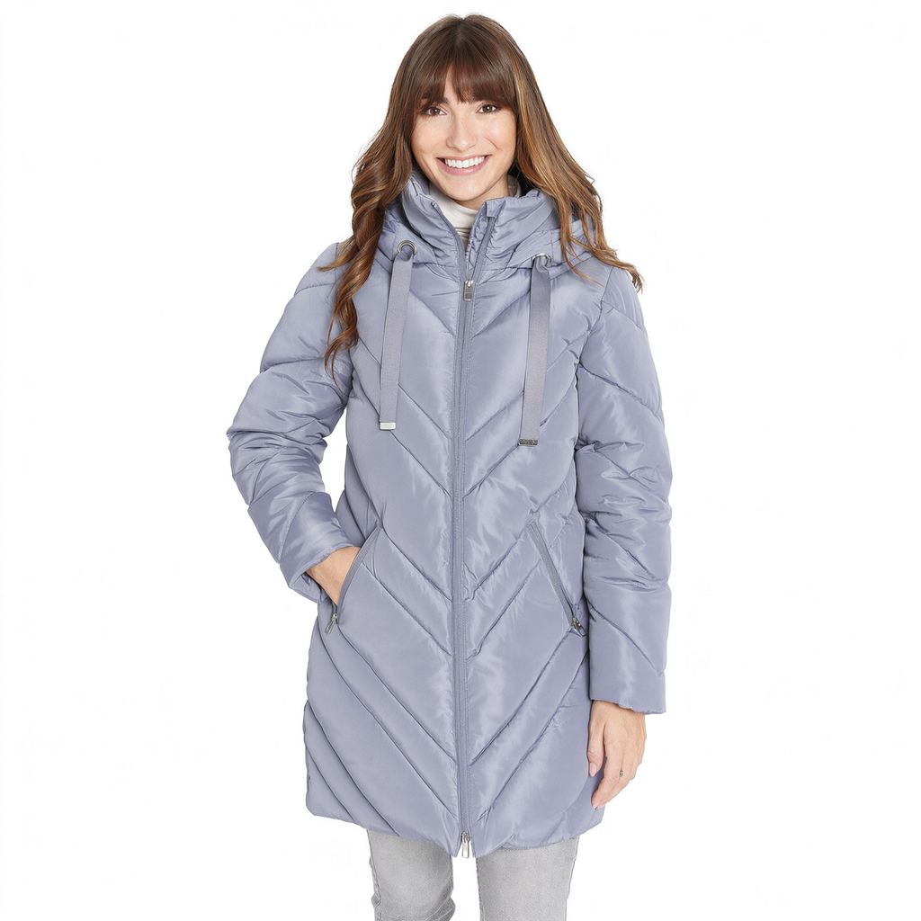 A woman wearing a light lavender-gray hooded puffer jacket with a chevron quilted pattern, standing against a plain white background.