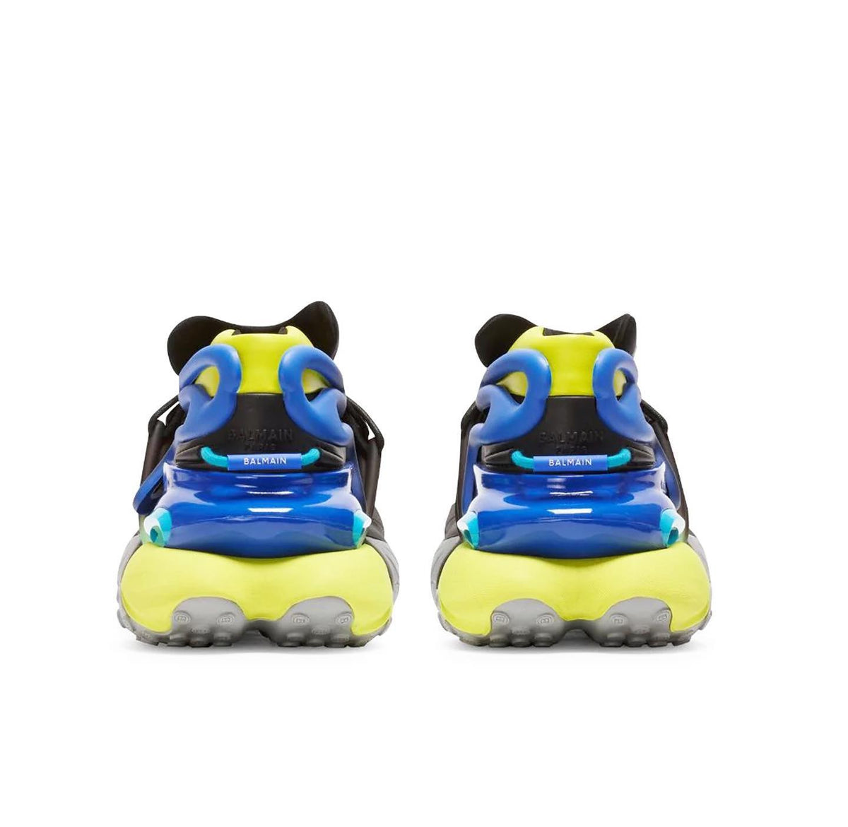 A pair of chunky sneakers shown from the back, featuring a bright neon yellow and blue design with black details and gray soles, set against a plain white background.