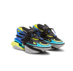 A pair of Balmain chunky sneakers in black, blue, and neon yellow, featuring a stacked midsole design and black laces, photographed on a white background.