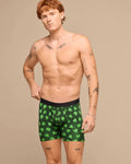 Man wearing green boxer briefs with shamrock pattern on a beige background