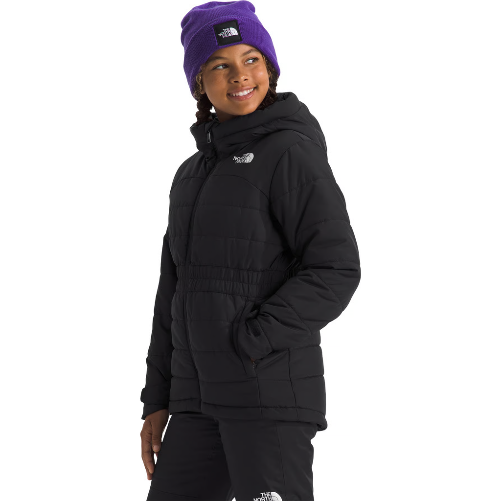A model wearing a black puffer jacket and matching black pants by The North Face, paired with a purple beanie, against a solid white background.