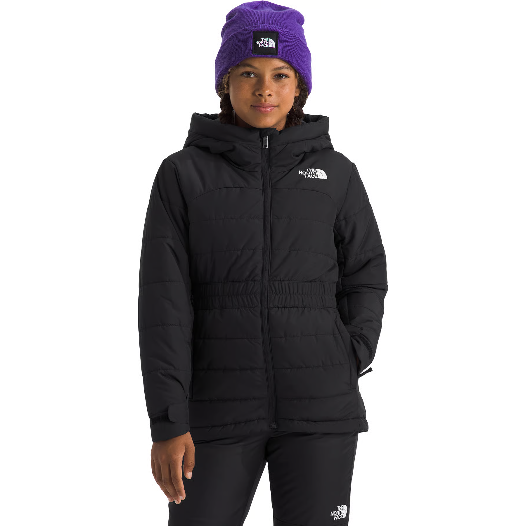A model wearing a black hooded puffer jacket and black pants from The North Face, paired with a purple beanie, against a solid white background.
