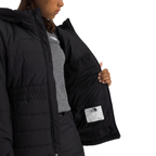 A close-up of a person wearing a black puffer jacket, opening the front to show the interior lining and a white interior brand label. The person is also wearing a gray top underneath.